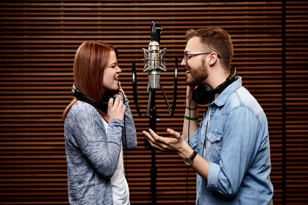 Two GCU Students singing in microphones at GCU Worship Recording Studio 