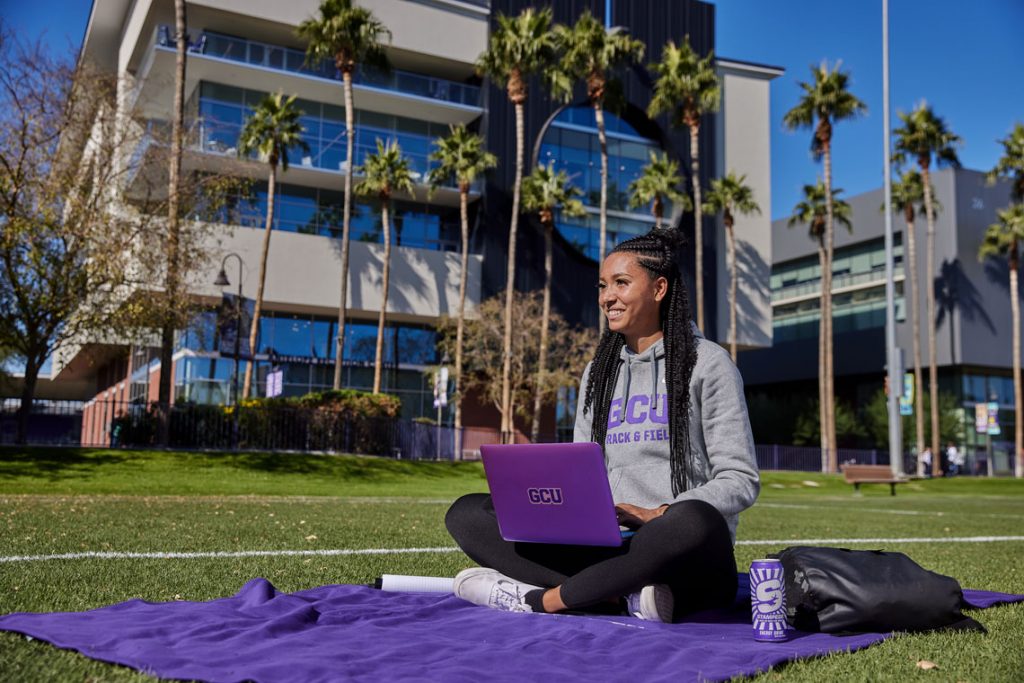 Student sitting in grass outside on GCU campus